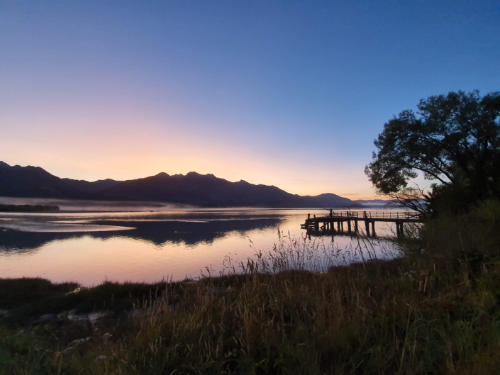 Sunrise reflected in Lake Wakatipu with wharf at Kinloch near Glenorchy