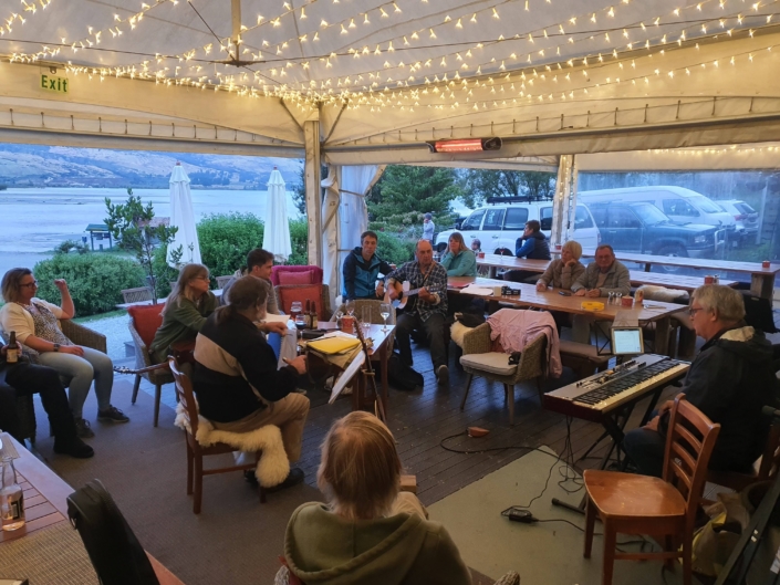 Small group of musicians and audience playing in restaurant marquee at dusk