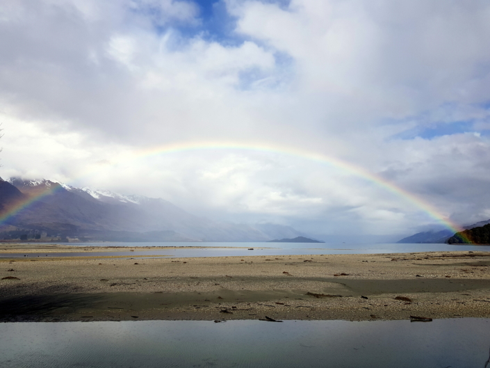 Rainbow across lake with mountains behind