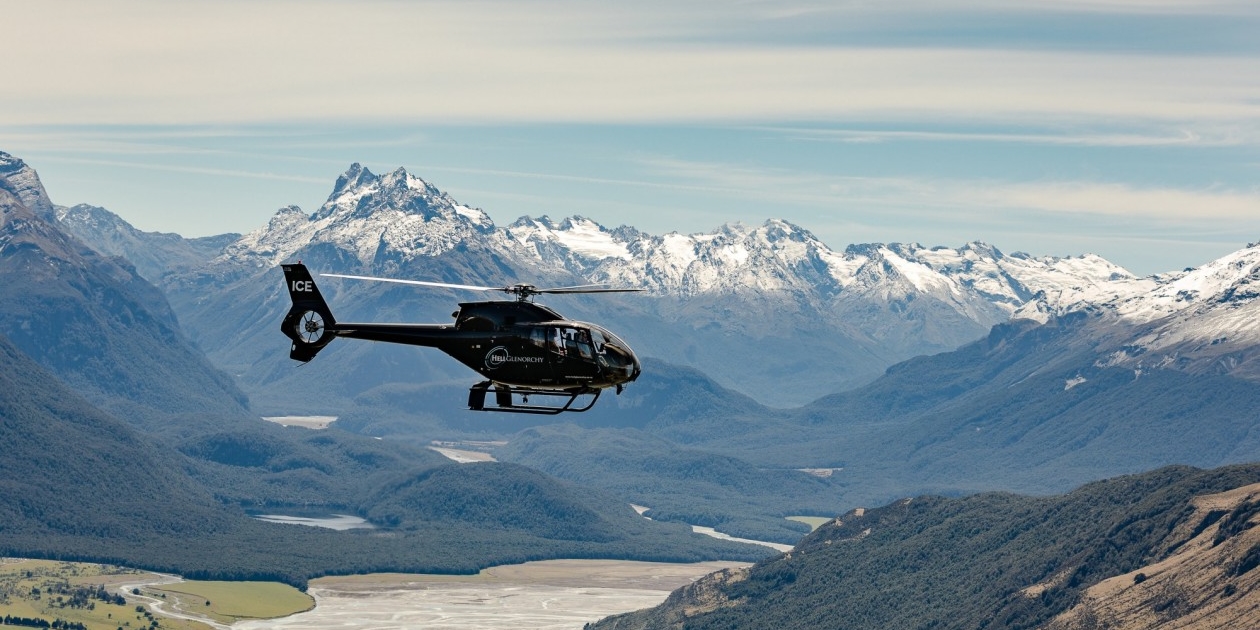 Helicopter flying in valley surrounded by mountains