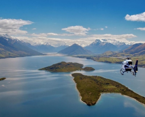 Helicopter flying towards Glenorchy over 2 islands in Lake Wakatipu