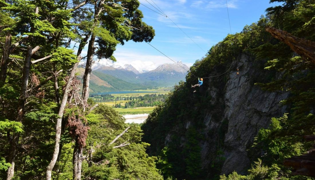 Person ziplining through canyon with mountain views