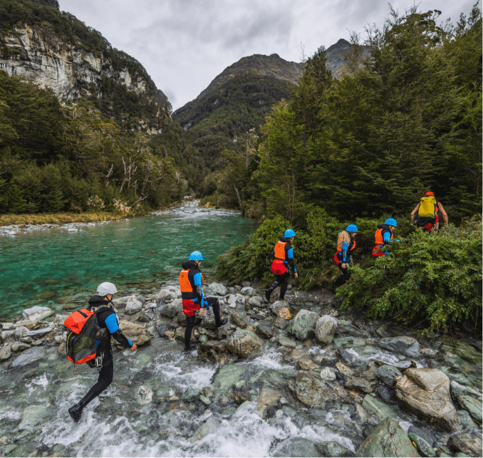 People in wetsuits crossing a river to go canyoning
