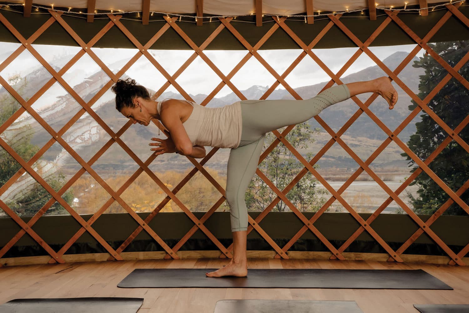 Yoga teacher doing warrior pose in yurt in front of Glenorchy mountain view